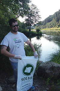 迈克尔拿着一个SOLVE俄勒冈清洁袋站在乌姆普夸河的Tyee段前。